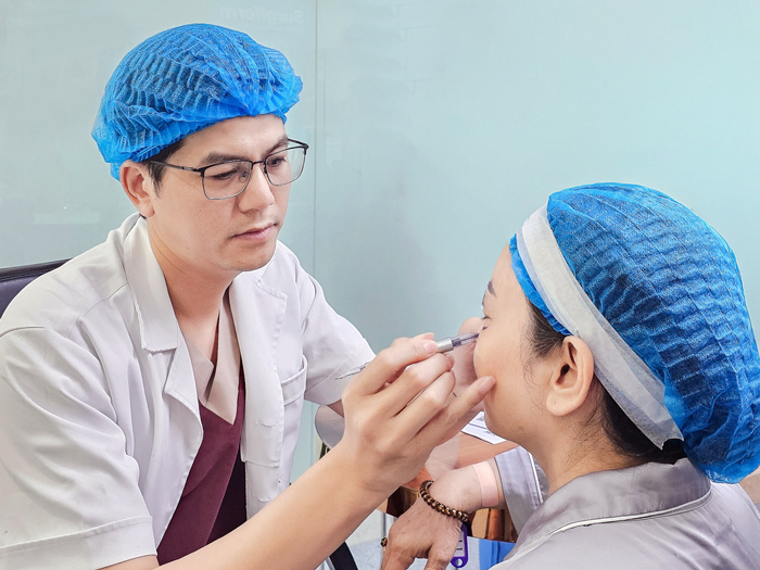 Bác sĩ Nguyễn Văn Huyên - Trưởng khoa Thẩm mỹ Hàn Quốc tại Bệnh viện Thẩm mỹ Kangnam Hà Nội thăm khám, xác định vi trí cần khắc phục ở mí mắt cho khách hàng