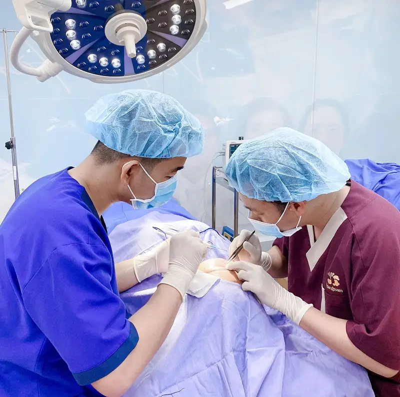 Bác sĩ tiến hành cắt mí, loại bỏ da dư, mỡ thừa và khâu vết thương bằng chỉ thẩm mỹ