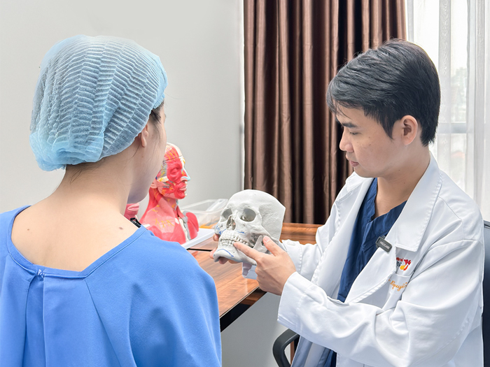Bác sĩ Kangnam phân tích tỷ lệ gò má cao và hàm thô trên mô hình trước khi thực hiện combo phẫu thuật.