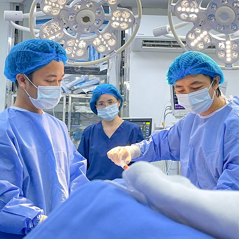 bác sĩ trong phòng phẫu thuật, thực hiện hút mỡ cho khách hàng với thao tác chính xác