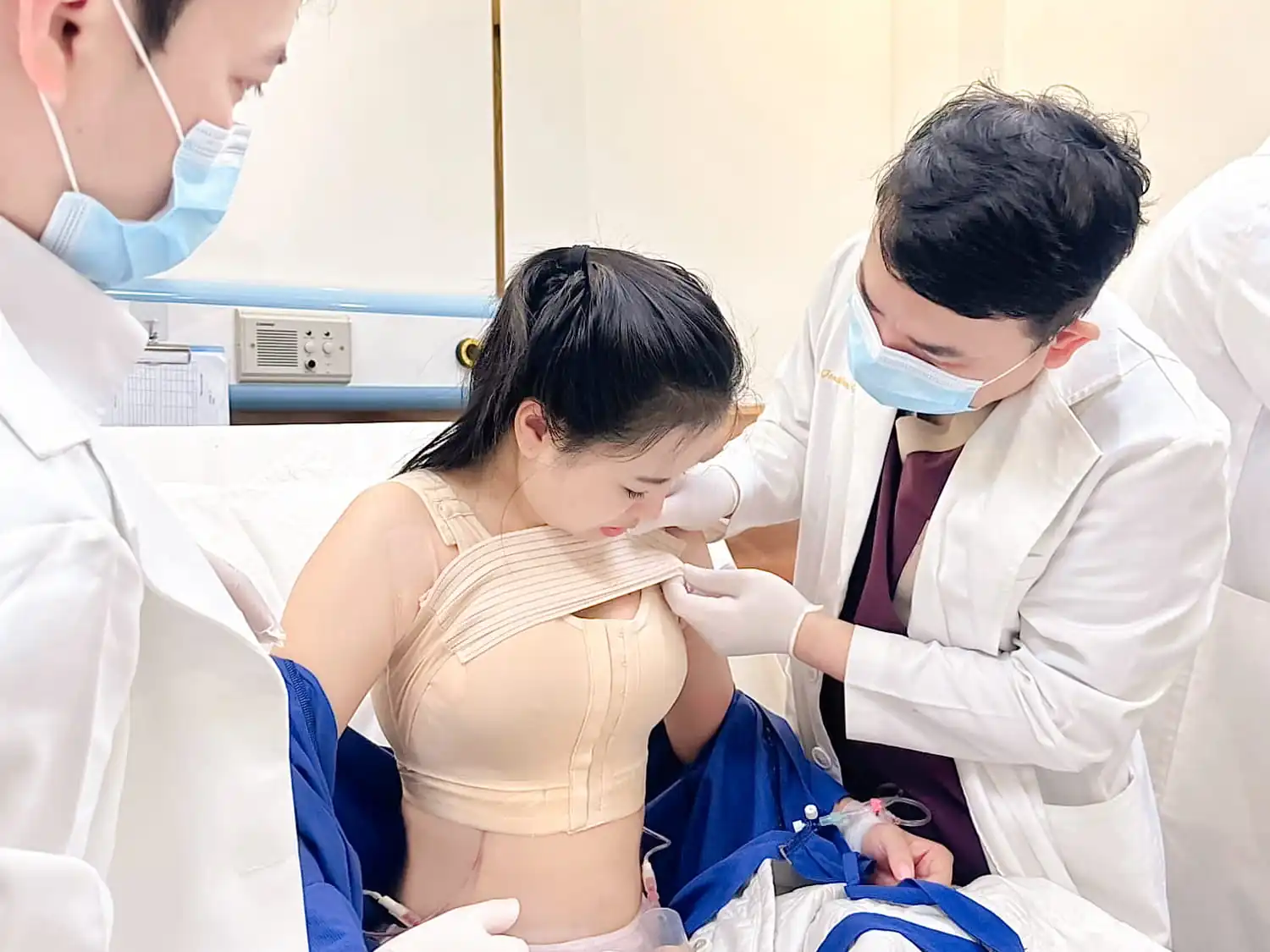 khách hàng được bác sĩ chăm sóc hậu phẫu, mặc áo ngực đình hình